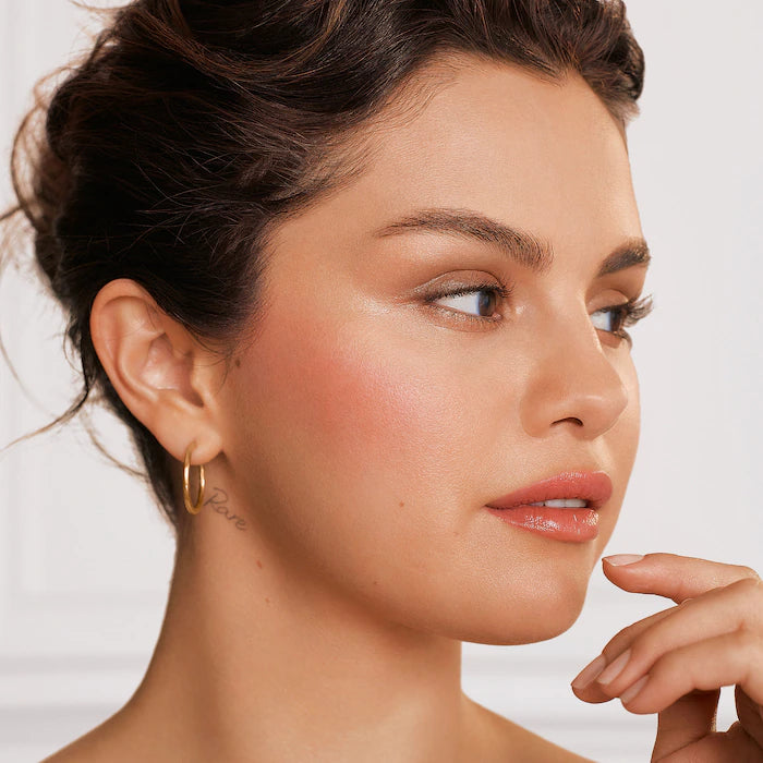 Rare Beauty Positive Light Luminizer on model cheekbones lit from within glow finish
